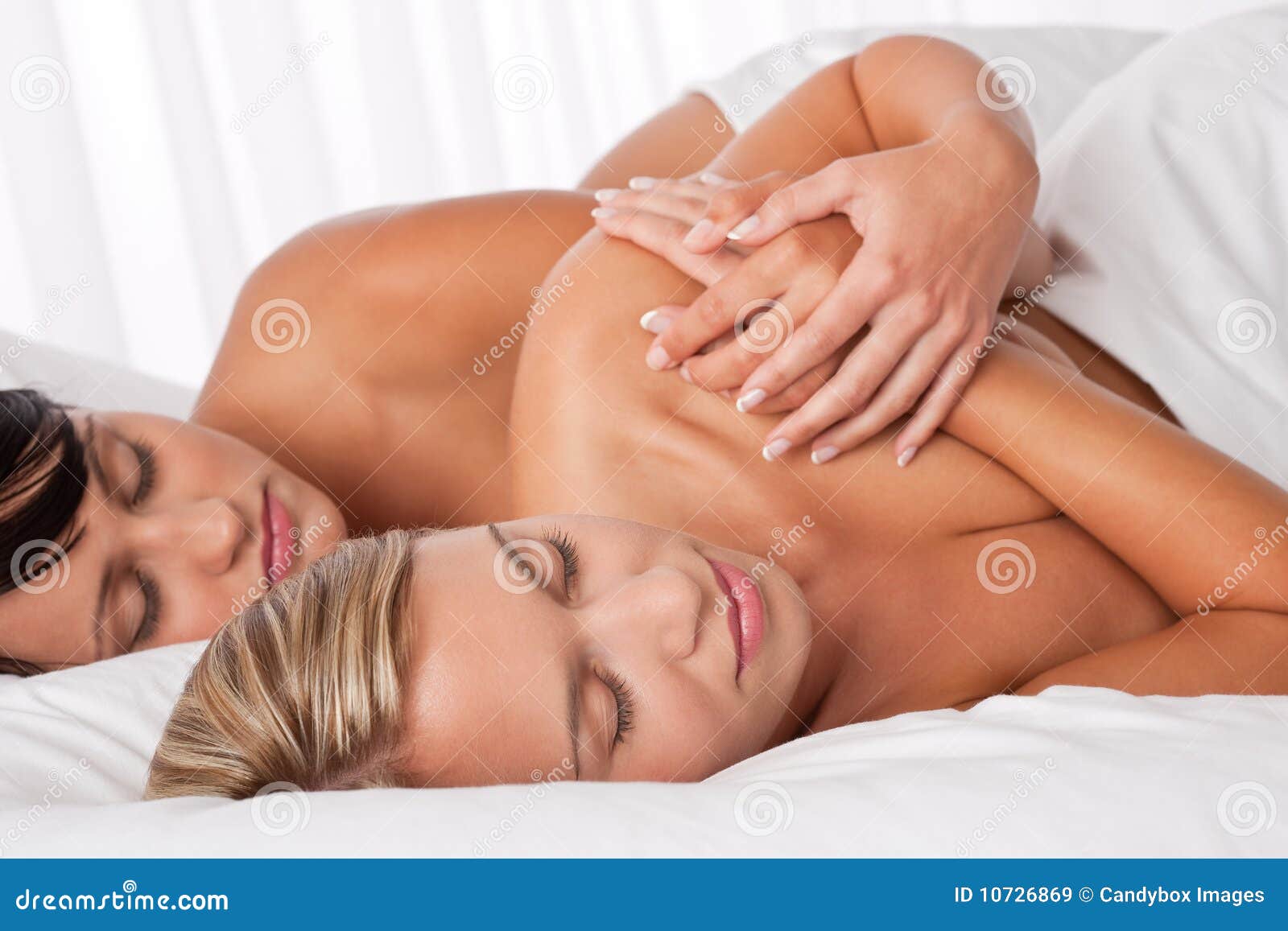 Two young women sleeping in white bed. Two young women lying down in white bed and sleeping together naked