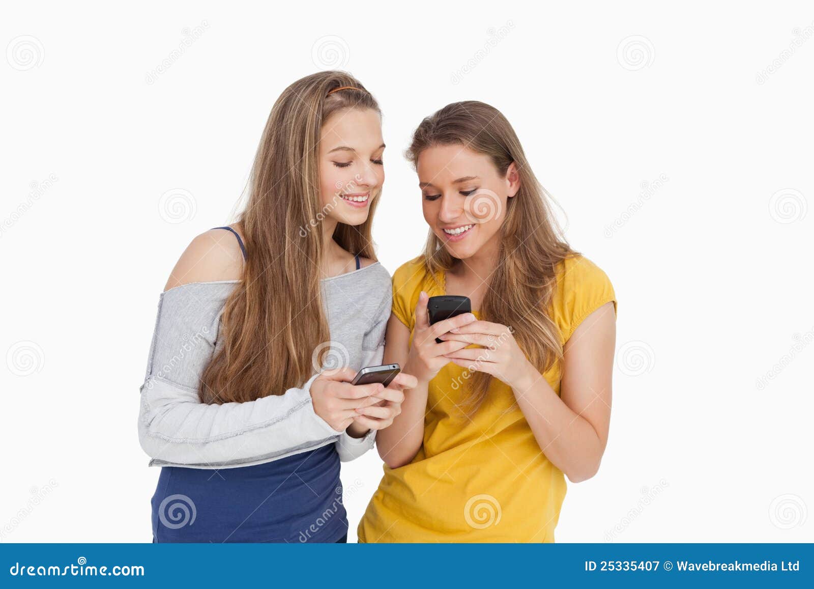 Two Young Women Smiling while Looking Their Cellphones Stock Image ...
