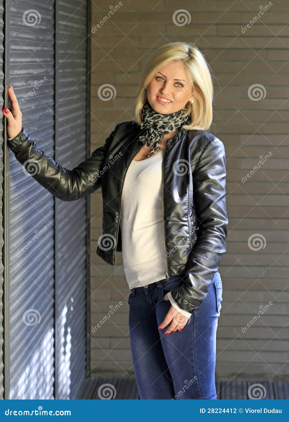 La femme blonde de type urbain a rectifié dans la jupe en cuir et des blues-jean