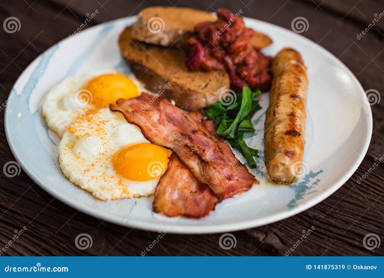 typial breakfast with eggs, bacon and sausage on plate