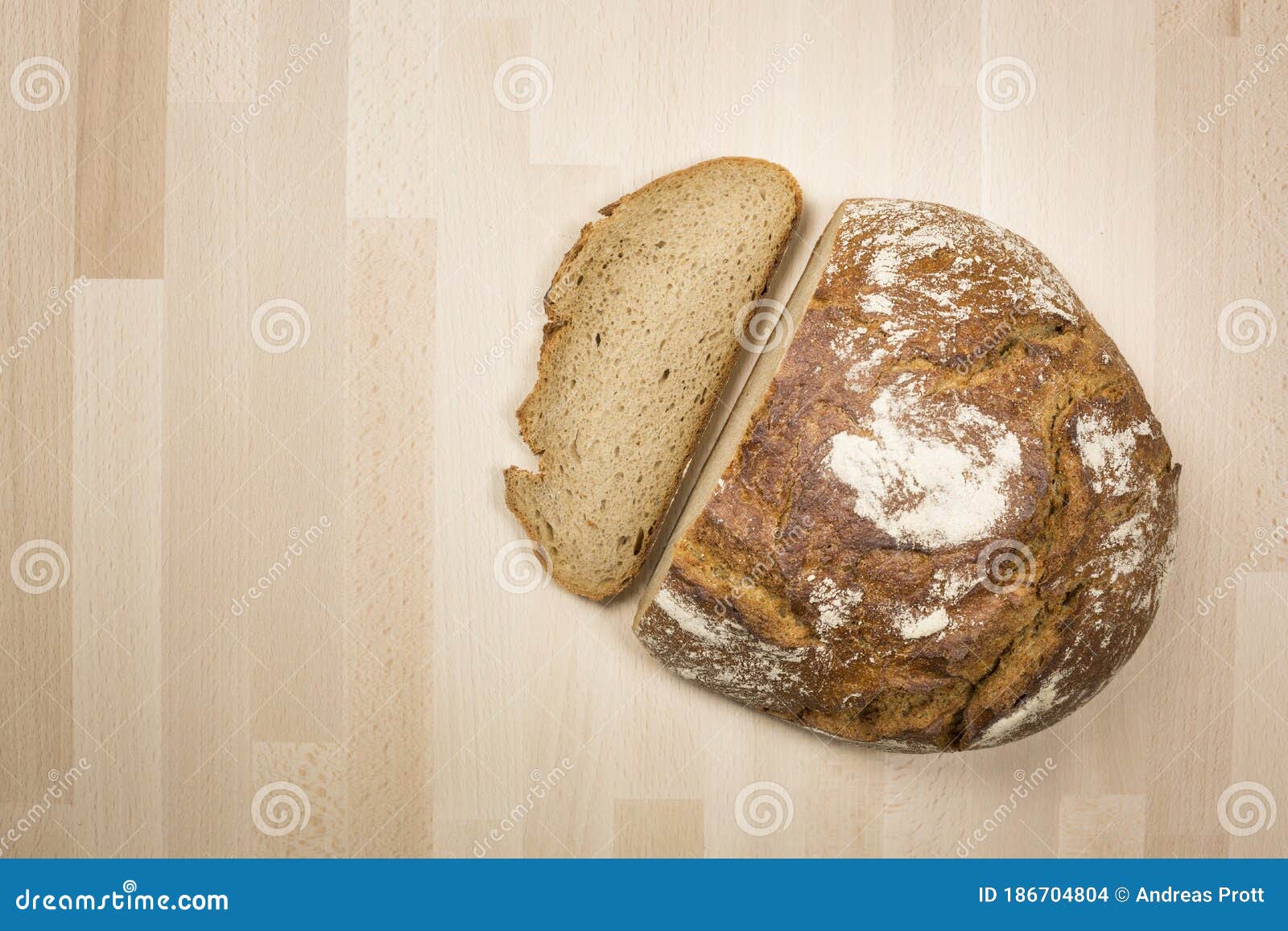 A Typical German Loaf of Bread and One Slice Lying on a Wooden Beech