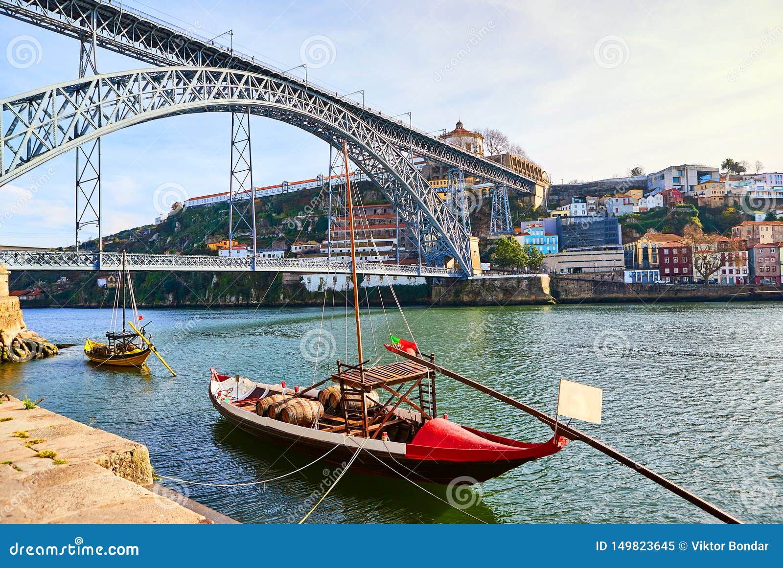typical portuguese wooden boats, called `barcos rabelos ` transporting wine barrels on the river douro with view on villa nova de