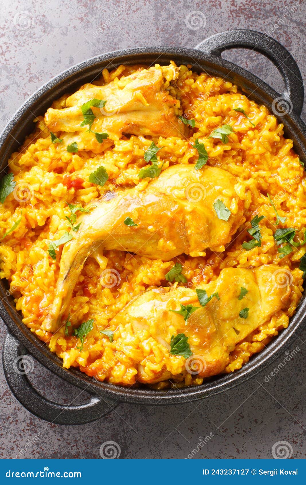 typical spanish rice with rabbit arroz con conejo closeup in the pan. vertical top view
