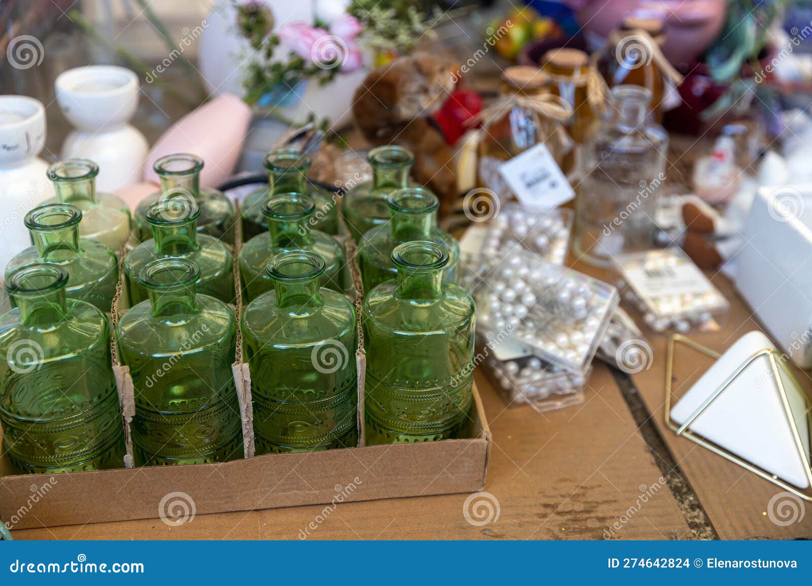 typical stall on els encants flea market at placa de les gloriesa. nine green figured juice or perfume bottles among sewing