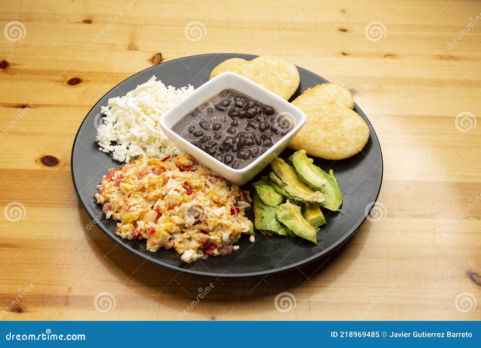 venezuelan breakfast scrambled eggs with tomato called perico, black beans, hard white cheese, arepas and avocado