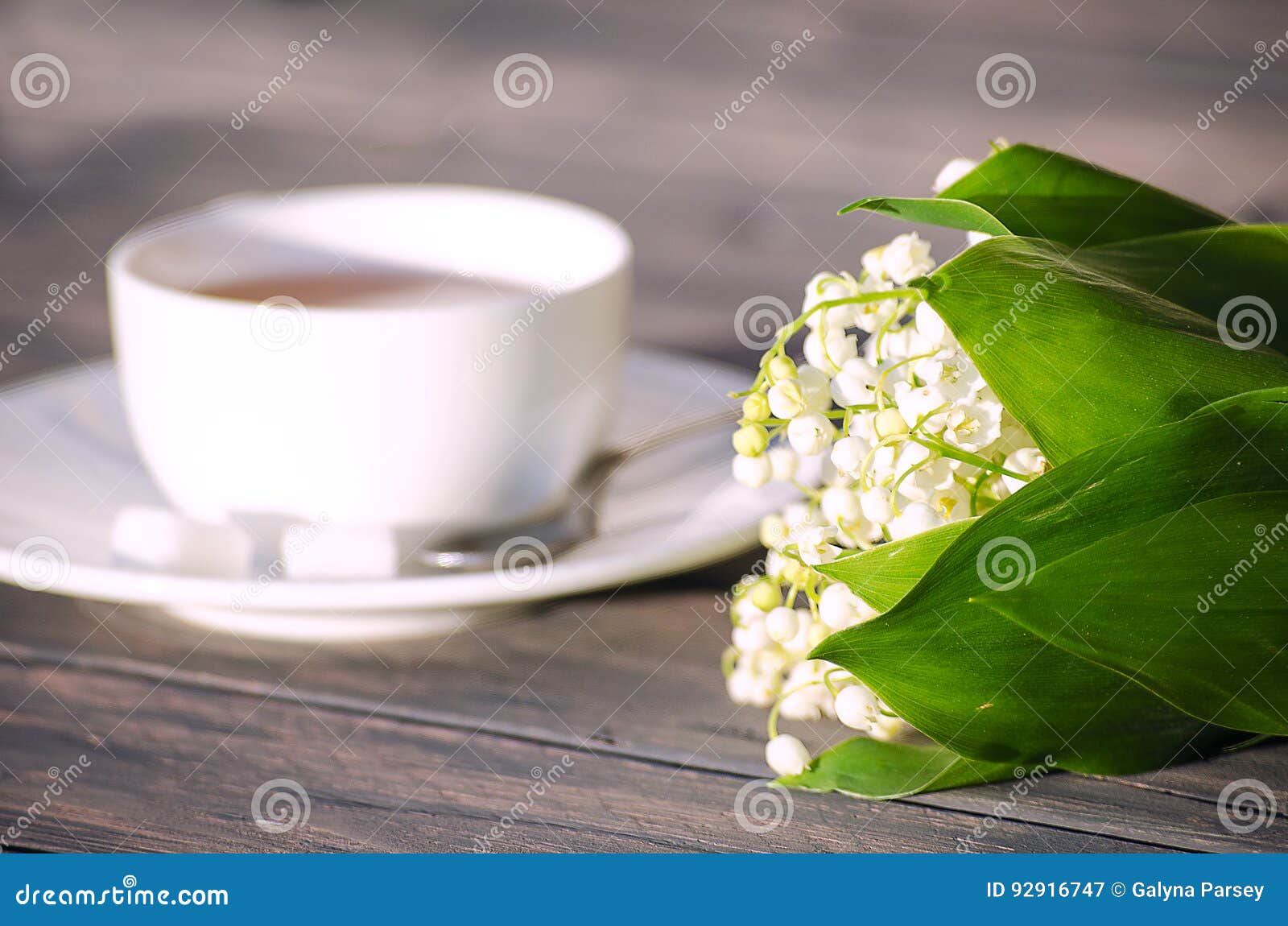 Té caliente en una taza blanca con un ramo de flores en un fondo de madera