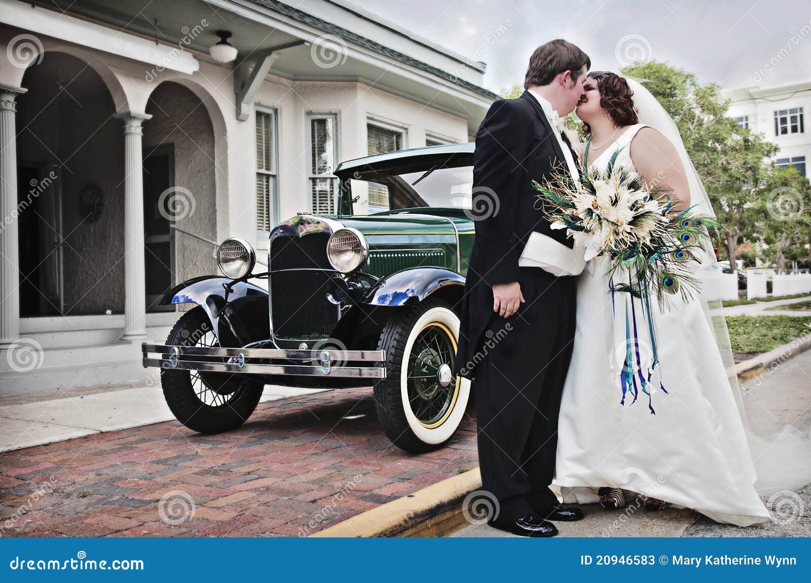 Uitstekend huwelijk. Een bruid en een bruidegom die zich voor het uitstekende auto kussen bevinden.