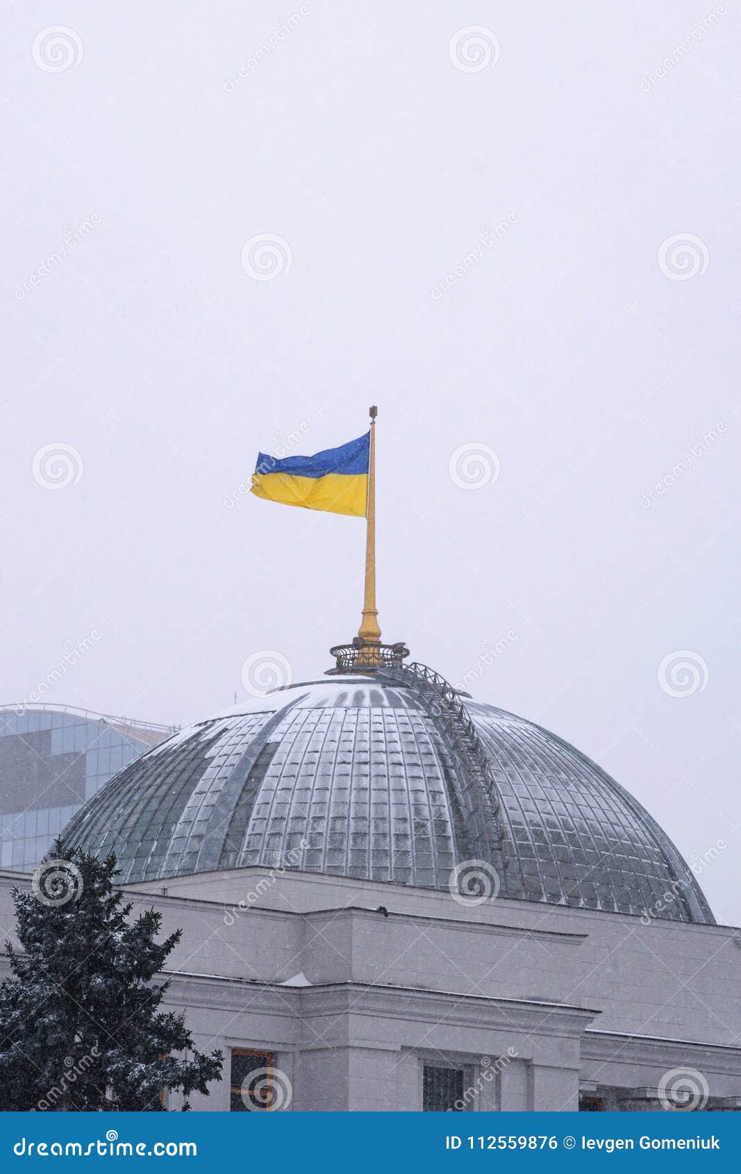 ukrainian flag waving over parliament verkhovna rada of ukraine in kiev, ukraine. snowfall morning