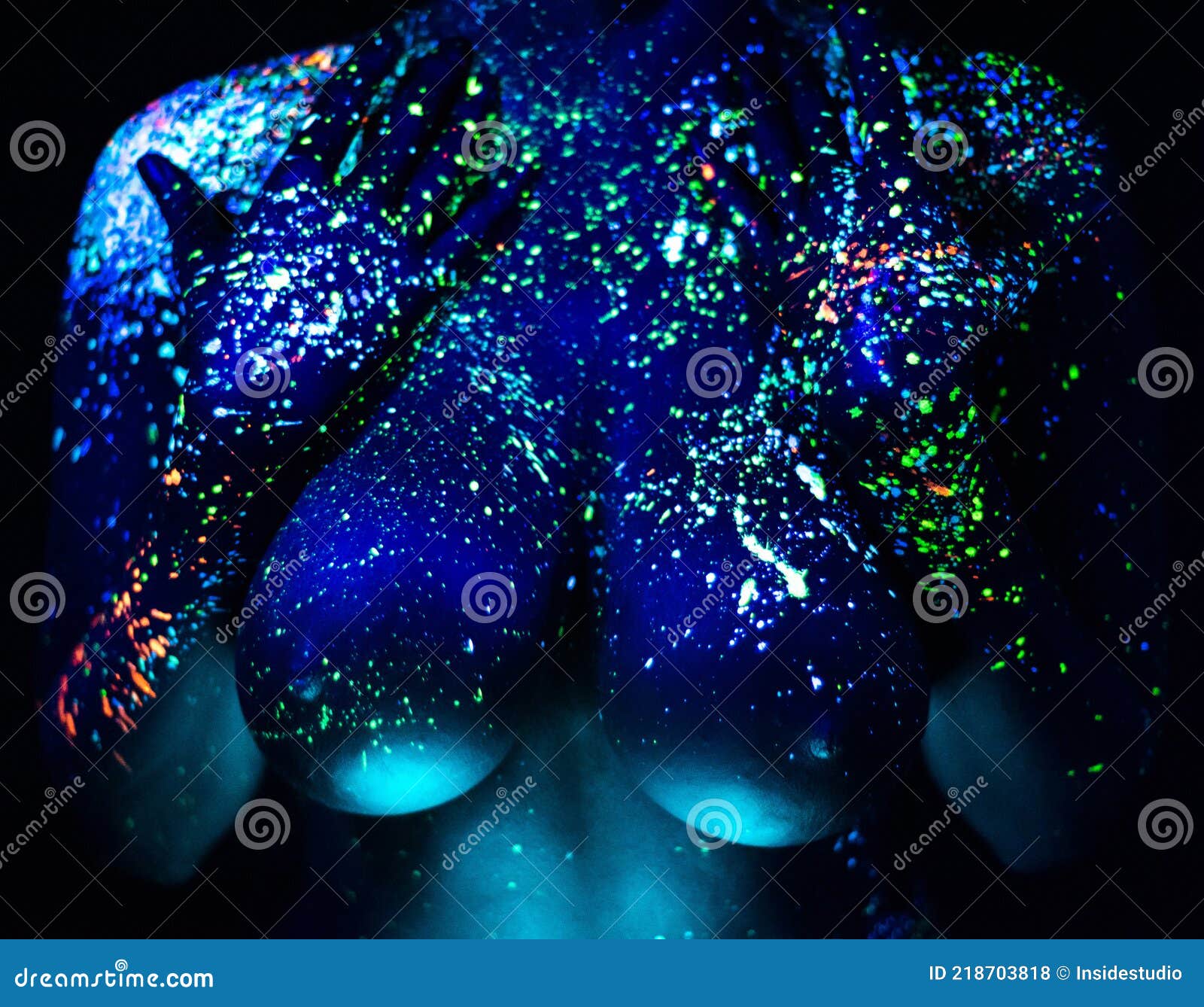 The girl is the image of the devil, contact lenses and with horns. Woman in  UV paint. fluorescent powder. Body art glowing in ultraviolet light. Stars  in the eyes. Stock Photo