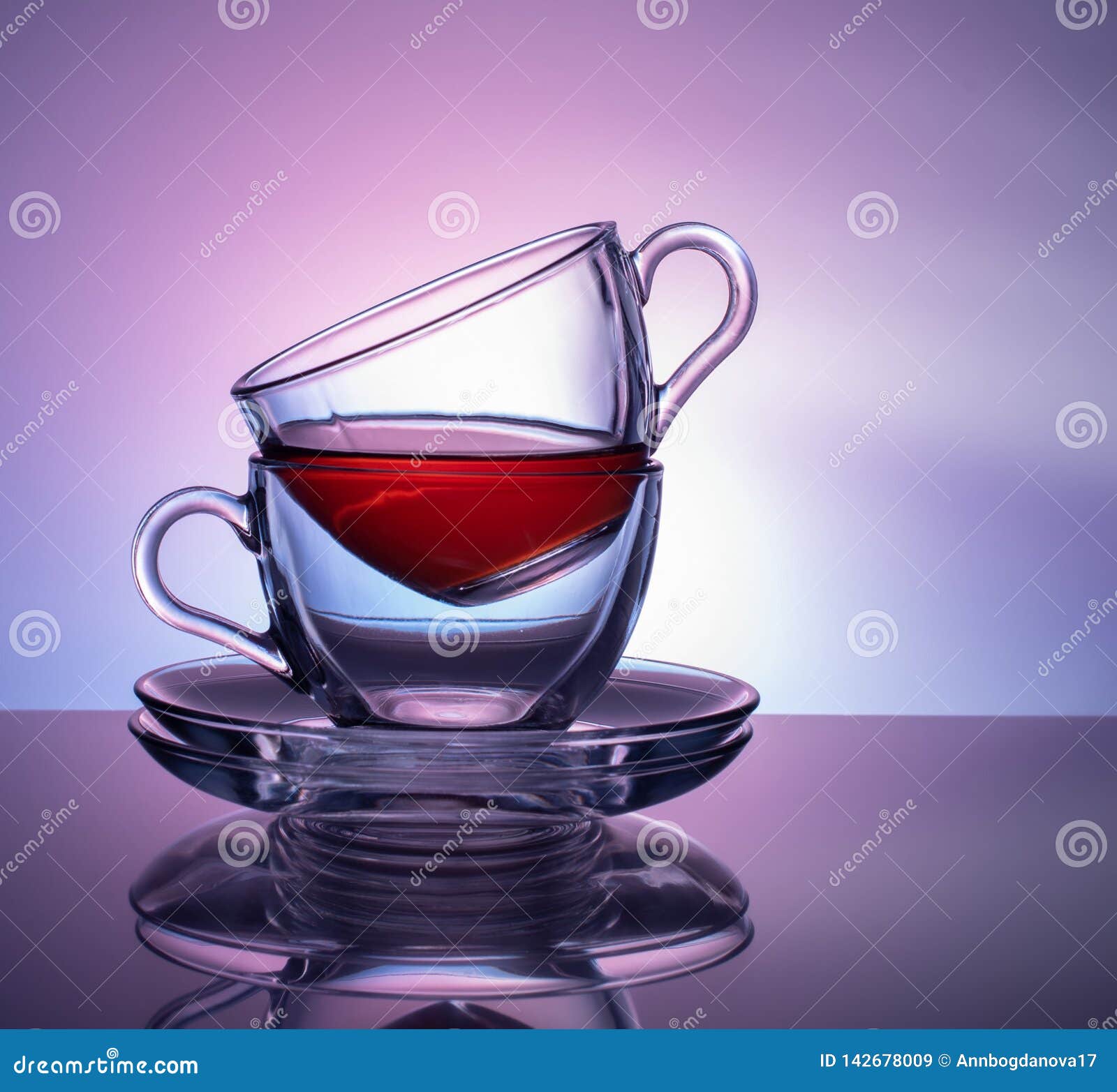 Um grupo de 2 copos de vidro para o chá em um fundo roxo e lilás Conceito. Um grupo de dois copos de vidro para o chá em um fundo roxo e lilás Conceito glassware Chá inacabado