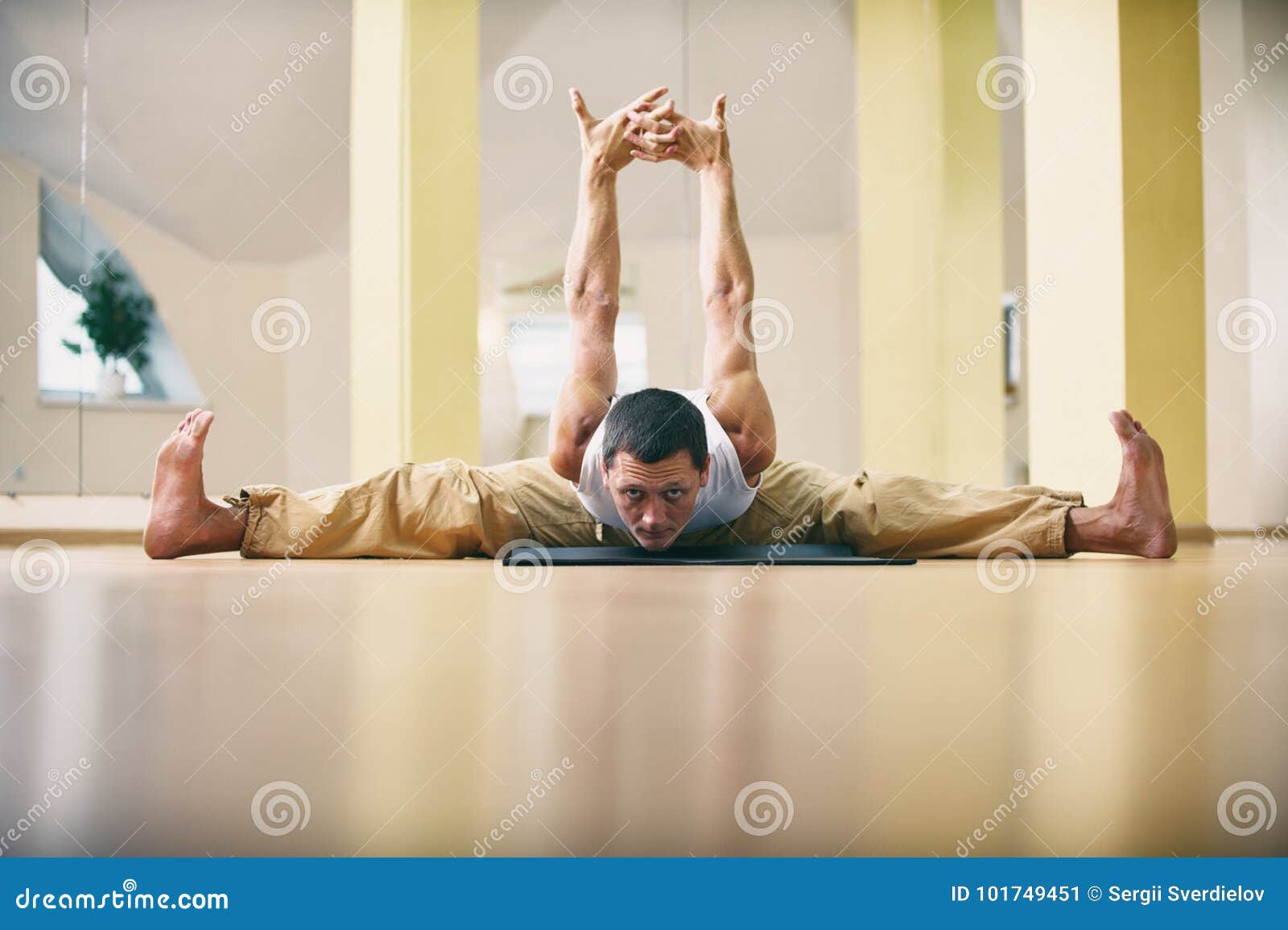 Um homem forte novo que faz a ioga exercita - a pose do ângulo reto de Samakonasana no estúdio da ioga