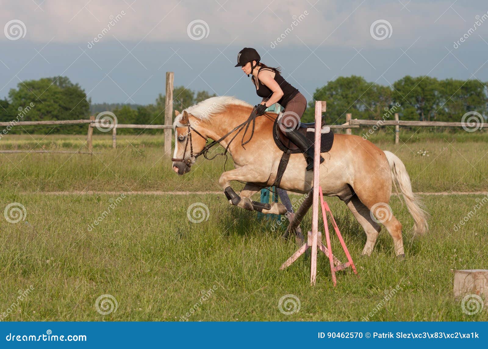 Há uma mulher montando um cavalo pulando sobre um obstáculo