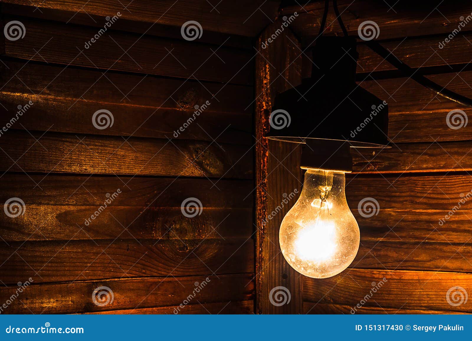 Uma lâmpada incandescente velha ilumina o canto de uma sala escura Eletrificação, pagamento para a eletricidade