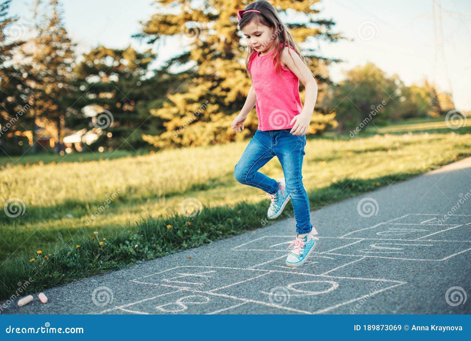menina asiática bonitinha jogando amarelinha ao ar livre. jogo de atividade  engraçado para crianças no playground
