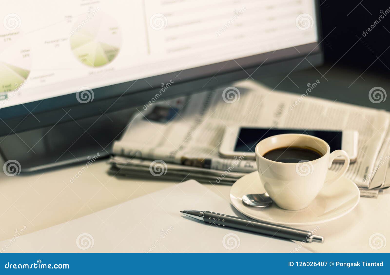 Uma xícara de café com jornal e telefone celular na mesa da. Uma xícara de café com jornal e telefone celular na mesa de um homem de negócios