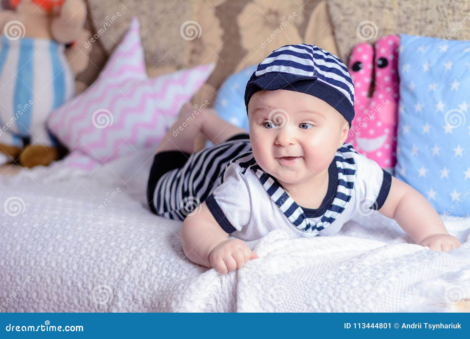 Un beau petit garçon dans un marin de costume s'étend sur un lit près des oreillers 2018