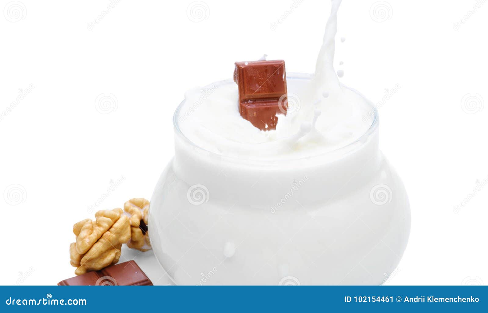 Un bicchiere di latte, dadi e un pezzo di cioccolato Il cioccolato cade nel latte Foto isolata sui precedenti bianchi. Un bicchiere di latte, noci e un pezzo di cioccolato il cioccolato cade in latte Una spruzzata di latte, una goccia di latte nell'aria Foto isolata su un fondo bianco Concetto orizzontale