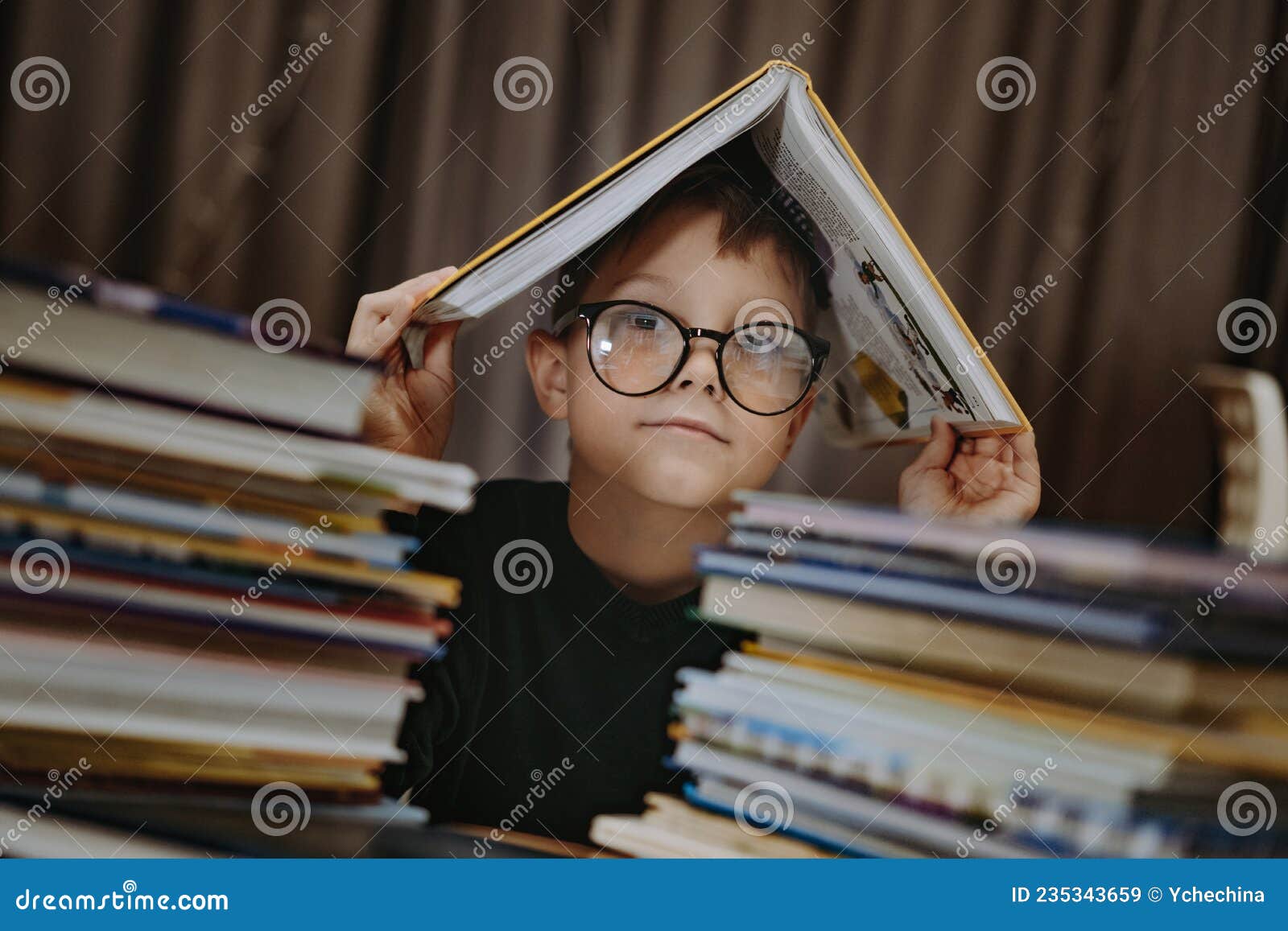 Un Chico Caucásico Lindo Con Gafas Cubriendo La Cabeza Con Un Libro. Niño  Alegre Mirando Desde Detrás De Pilas De Libros Imagen de archivo - Imagen  de kindergarten, muchacho: 235343659