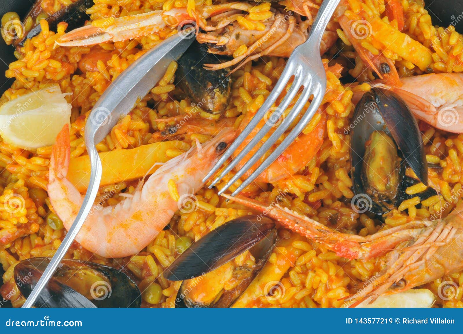 Un cierre de la paella para arriba. Arroz, camarones y mejillones en un primer del plato de la paella