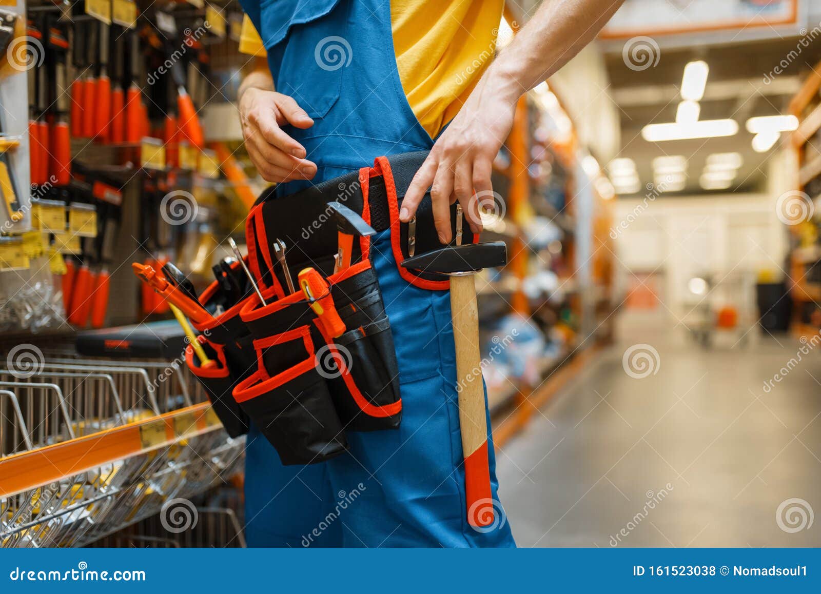 Homme Constructeur Choisissant La Ceinture à Outils Sur L'étagère En  Quincaillerie. Constructeur En Uniforme Regarde Les Marchandises Dans La  Boutique De Bricolage