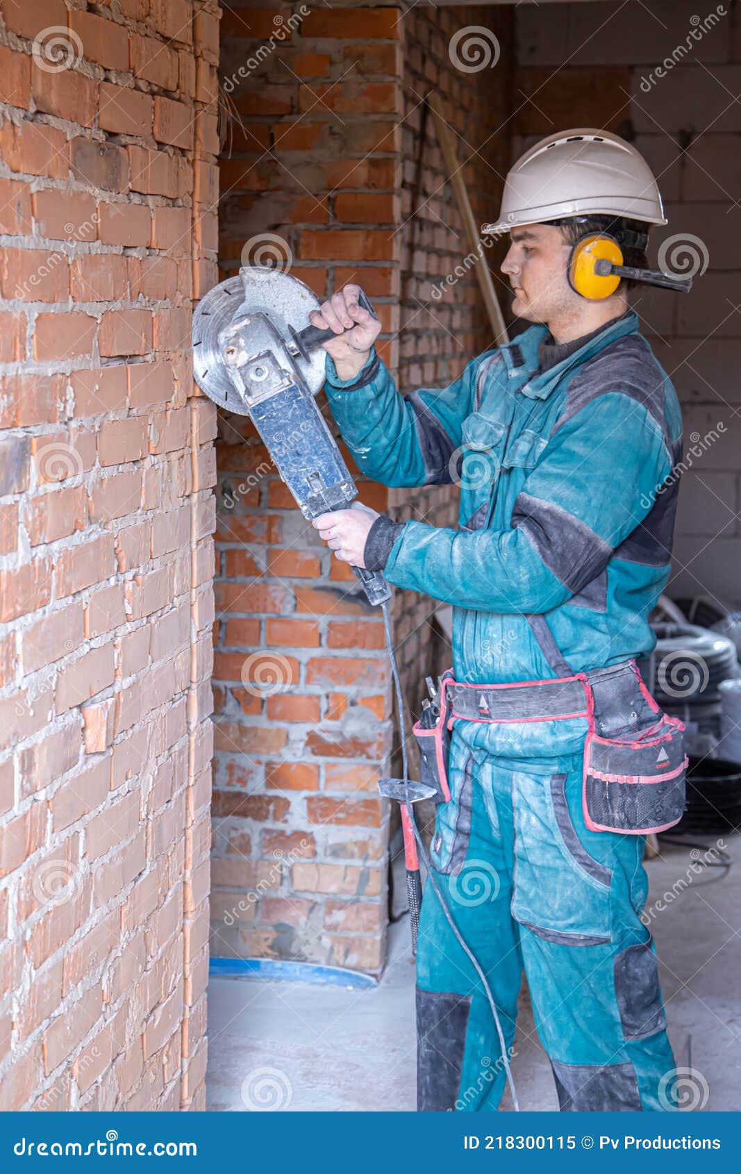 Un Constructor En Ropa De Trabajo Trabaja Con Una Herramienta De Corte de archivo - Imagen de hierro, casco: 218300115