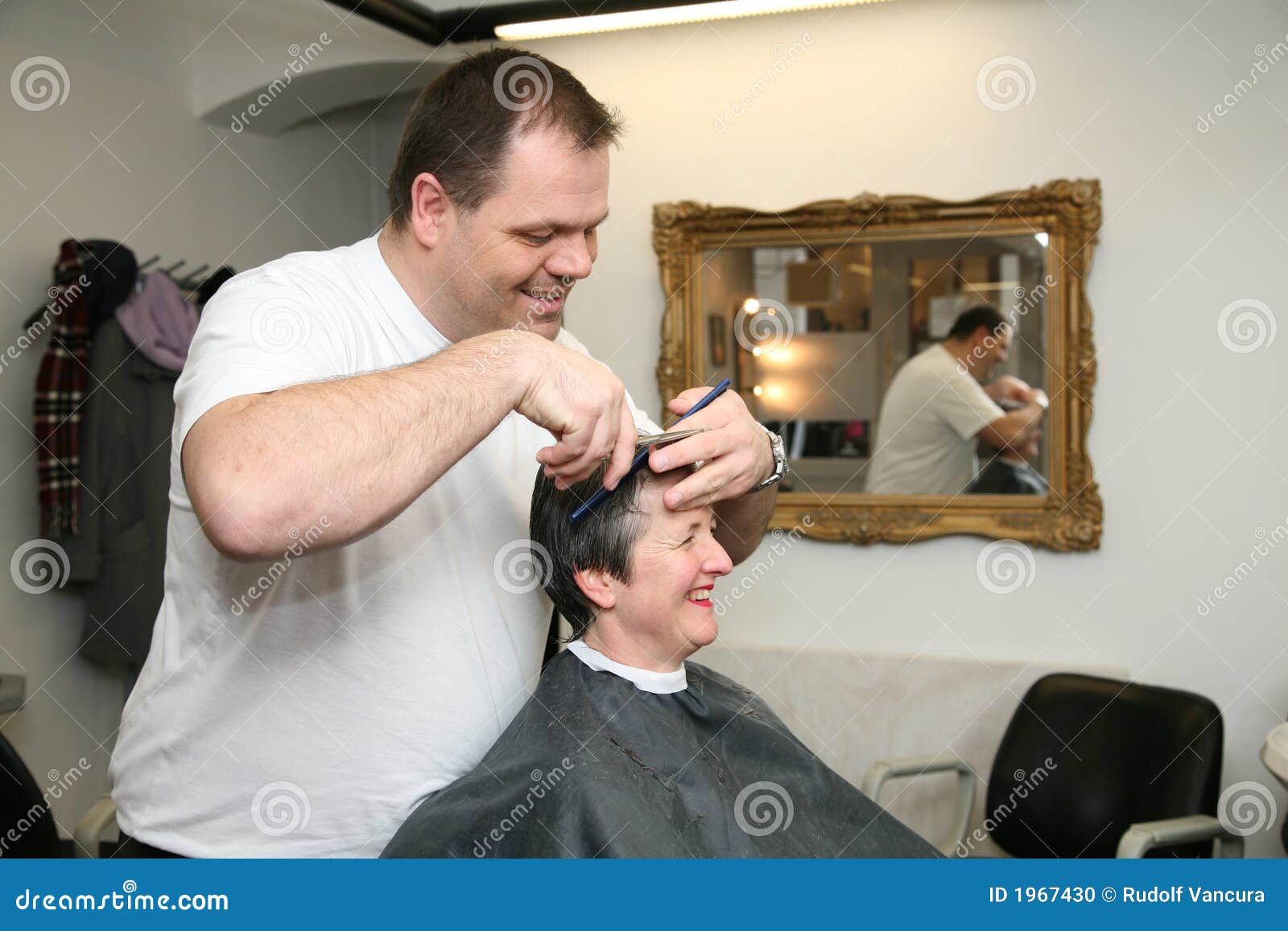 Un corte de pelo para una señora en los peluqueros. Mujer en un departamento de peluqueros, consiguiendo un corte de pelo. El peluquero y el cliente son graciosamente ellos mismos.