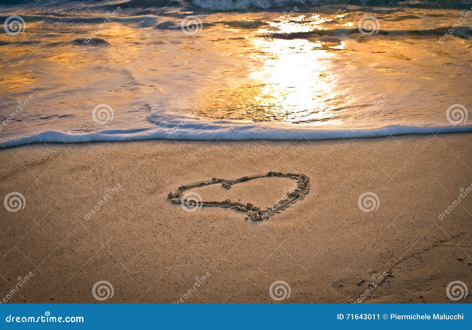 Un cuore sulla spiaggia al tramonto Immagine Stock