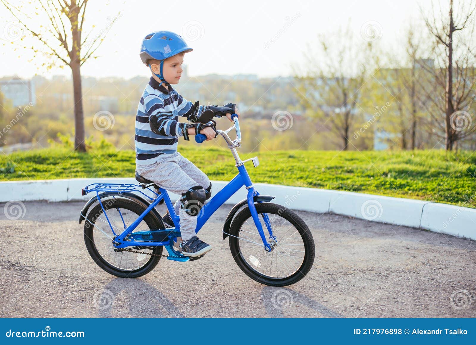 Un Enfant En Casque Et Protection En Vélo Sur La Nature Au Printemps Photo  stock - Image du exercice, heureux: 217976898