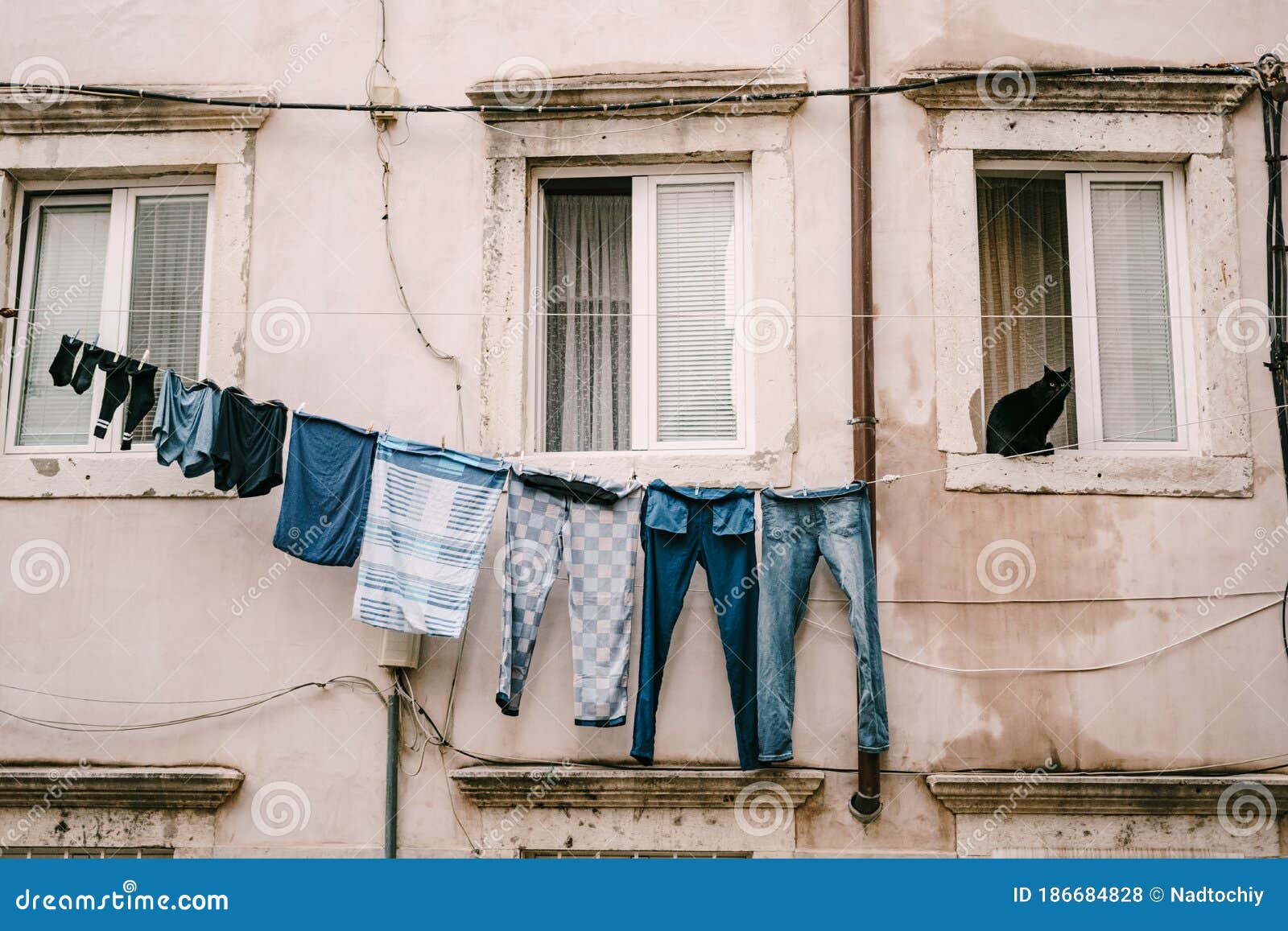 Un Gato Negro Sentado En Una Ventana. La Ropa Se Seca En Un Tendedero Entre  Las Ventanas. Foto de archivo - Imagen de ventanas, piedra: 186684828