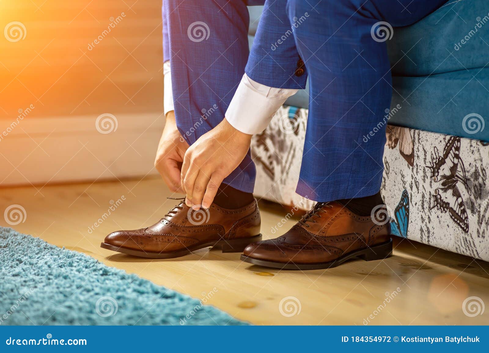 Un Hombre Ata Sus Cordones En Sus Zapatos Marrones En La Habitación. Traje Azul Y Zapatos De Charol Foto de archivo - de azul, detalle: 184354972