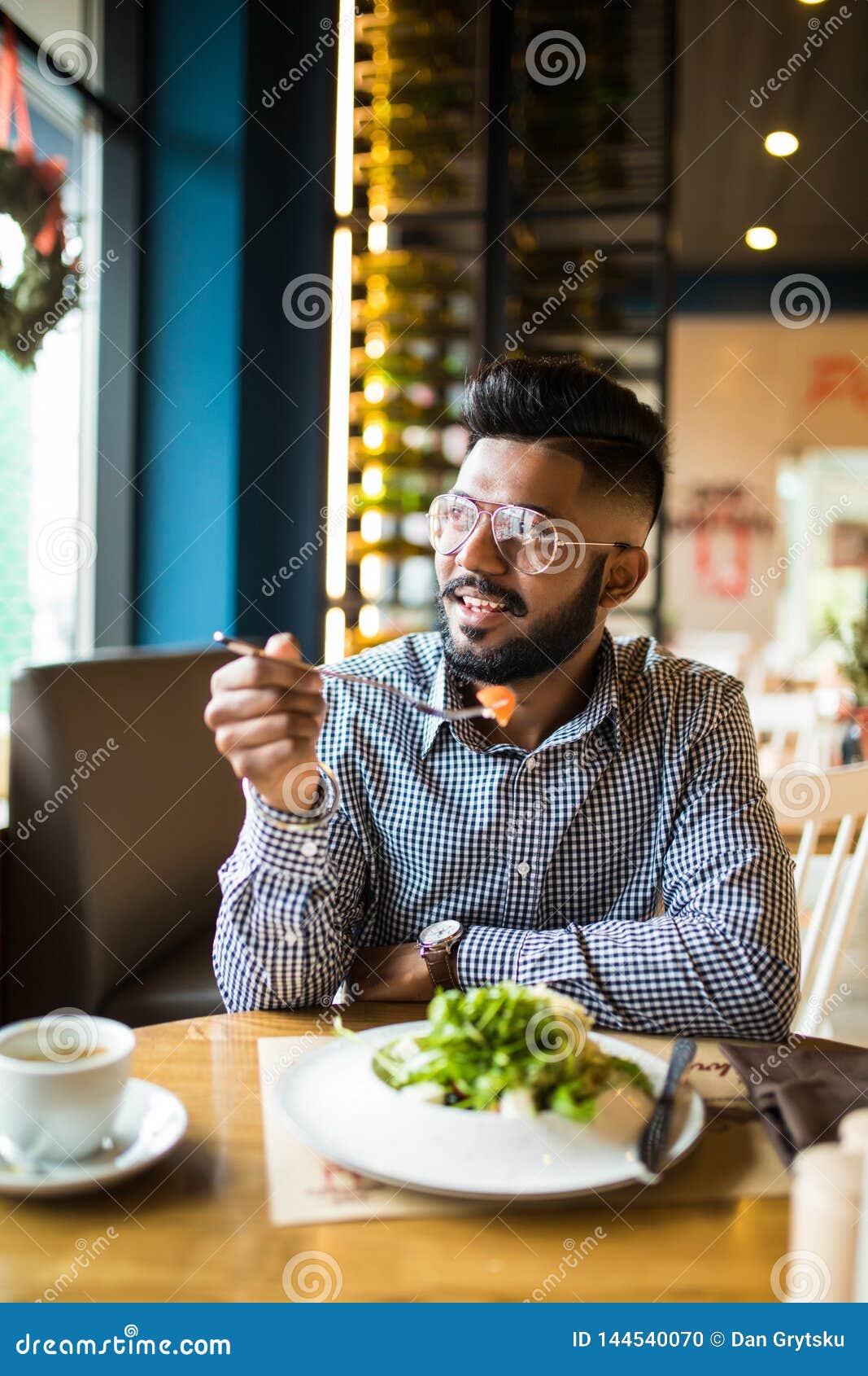 Un Hombre Barbudo Indio Guapo En Camisa a Cuadros Sosteniendo Un Tenedor Comiendo En El Cafe Y Sonriendo Mirando La Camara Foto de archivo Imagen de ocasional alegre 144540070