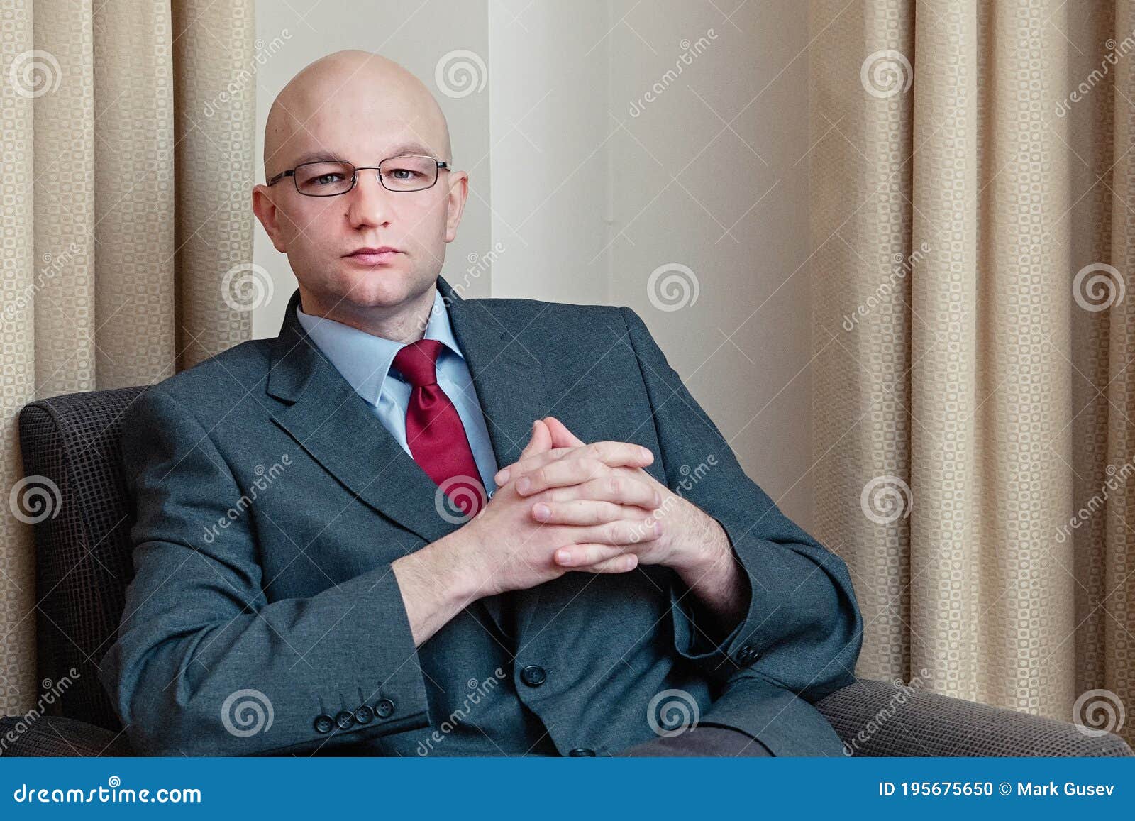 Un Hombre Negocios Calvo Y Atractivo De Traje Gris Camisa Azul Corbata Roja Gafas Sentado En Una Silla En Una Habitación De H Foto de archivo - Imagen de formal,