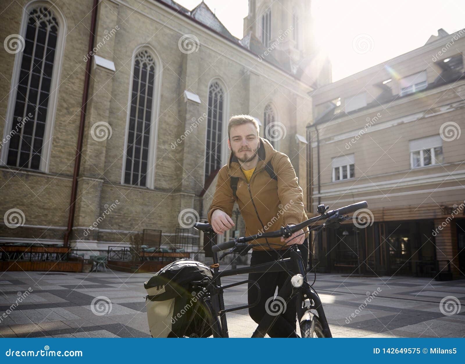 Un jeune homme, 20-29 années, posant avec sa bicyclette dans une belle place de ville en Europe, la Serbie, Novi Sad