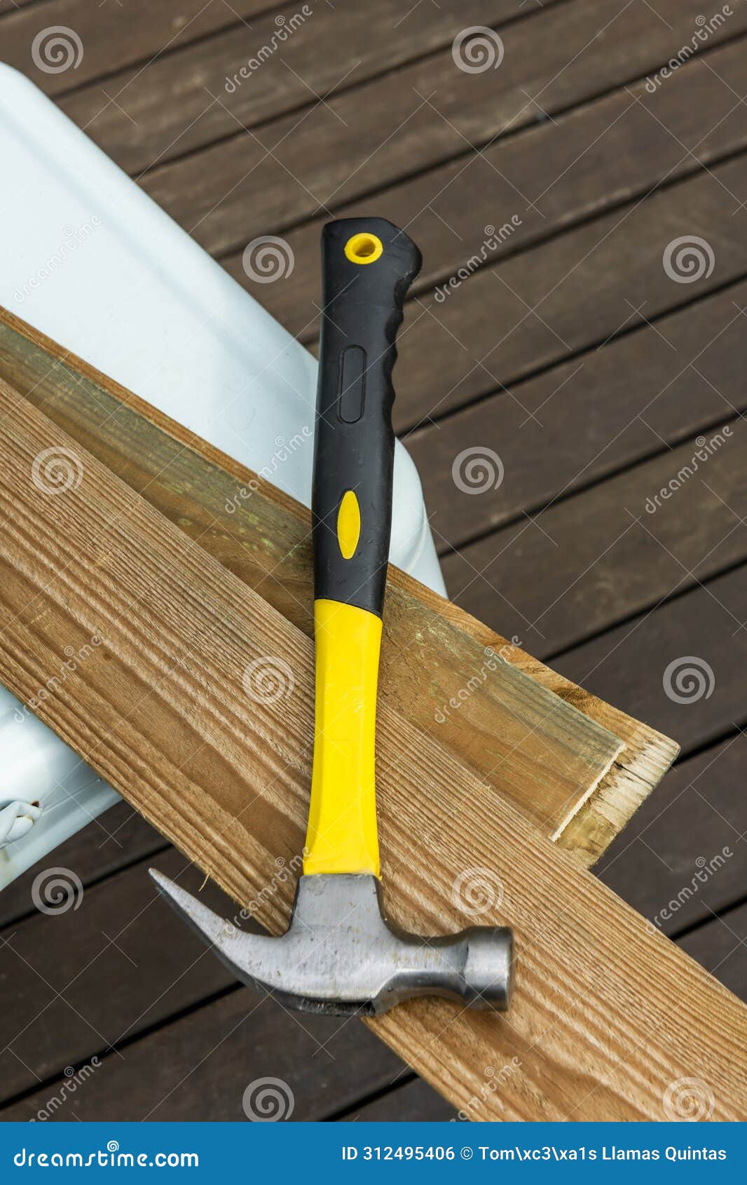 un martillo metÃÂ¡lico con mango de madera amarilla y negra sobre unos tablones de madera