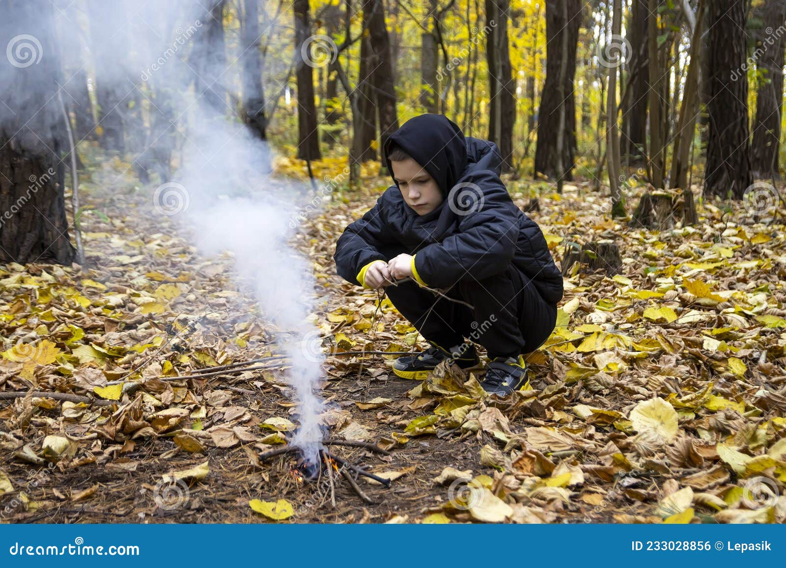 Un Niño En El Bosque Está Encendiendo Un Fuego. Concepto : Perdido