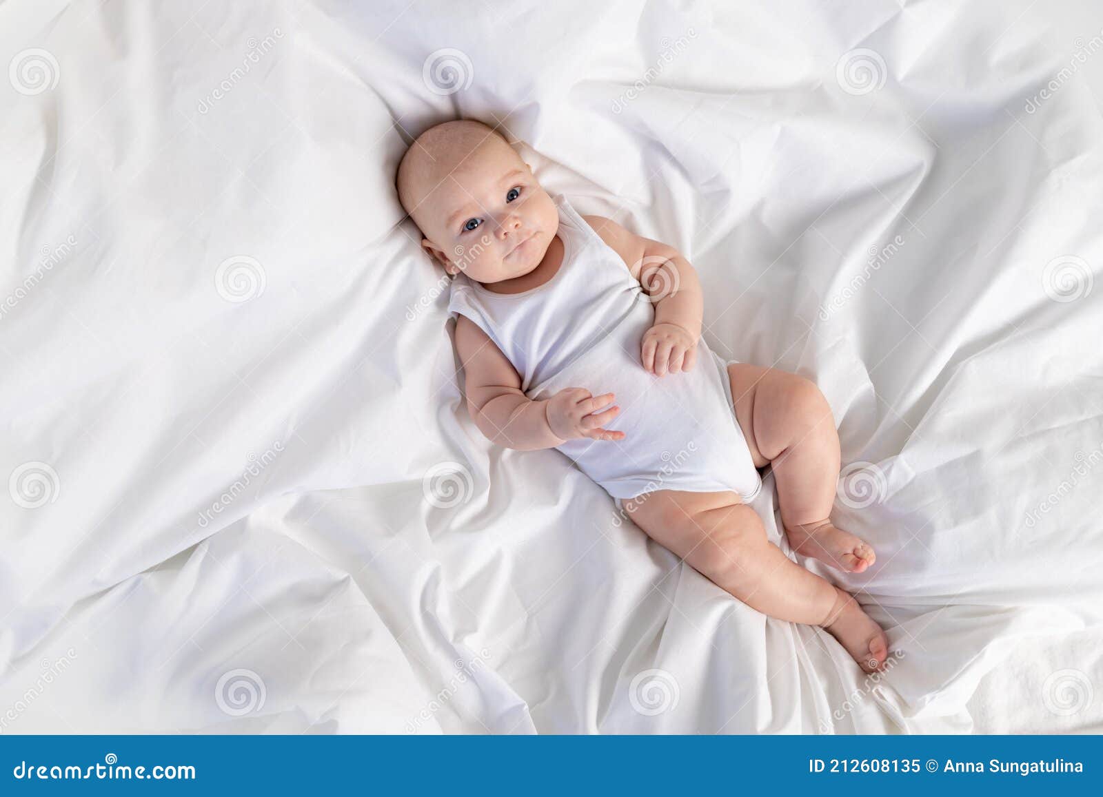 Un Niño En Una Cama Blanca Por La Mañana. Textiles Ropa De Cama Para Niños. Un Bebé Recién Nacido Se Ha Despertado O Se Va a La Imagen de archivo -