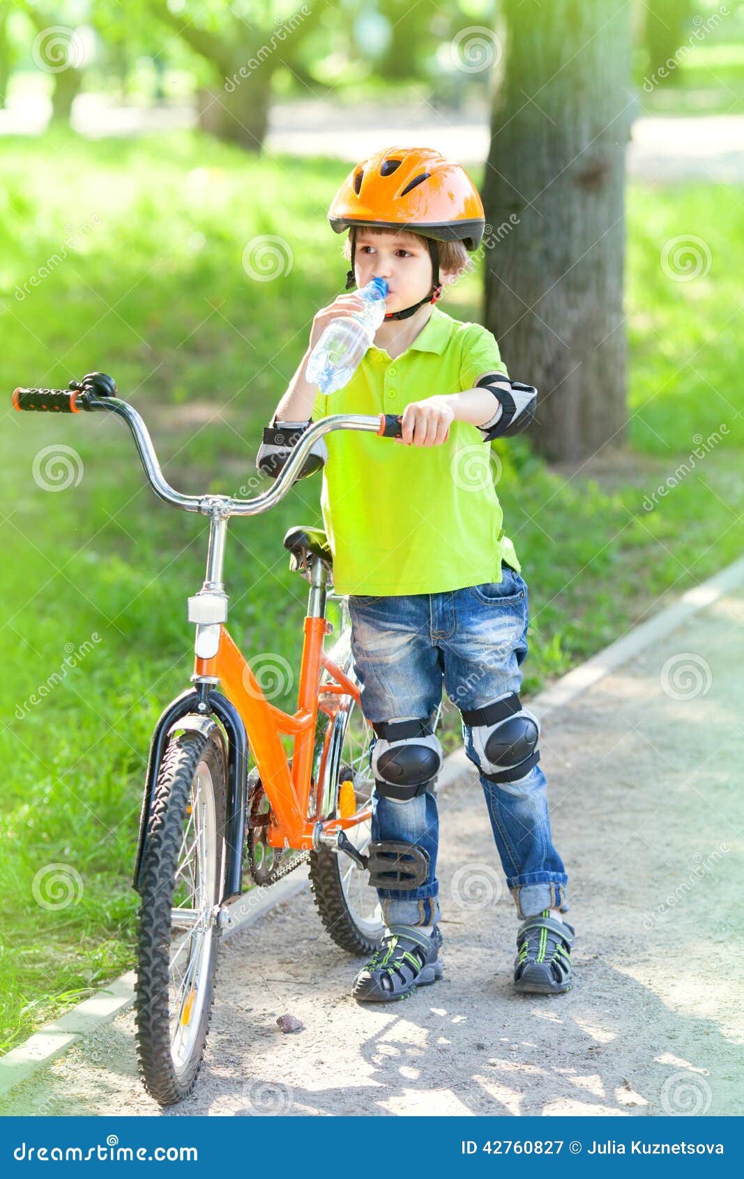 Un Niño Pequeño Con Una Bicicleta Bebe El Agua Imagen de archivo