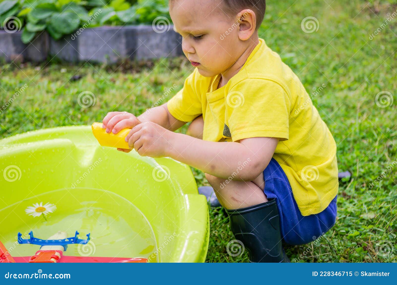 Un Niño Juega Con Juguetes El Baño De Agua Al Aire Libre Imagen de archivo - Imagen de juegos, feliz: 228346715