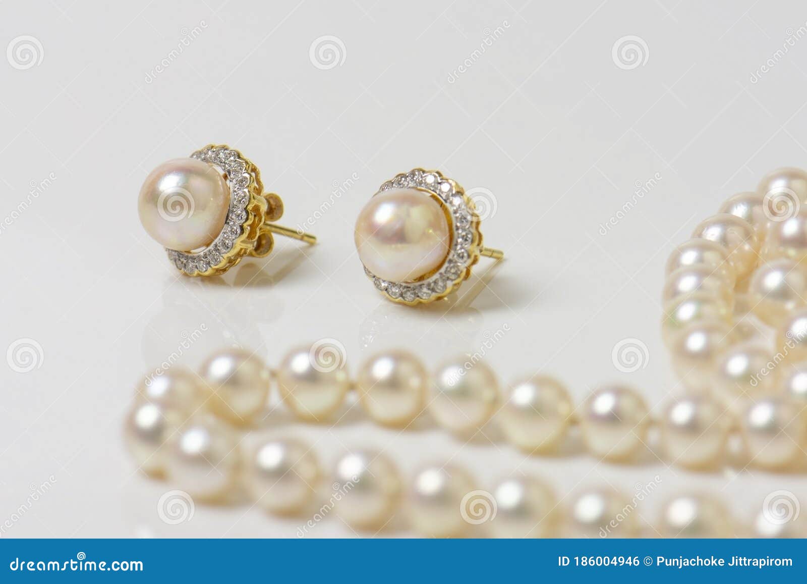 Un Par De Aretes De Perlas Naturales Sobre Blanco Con Collar De Perlas Al Fondo. Foto de archivo - compuesto, poste: 186004946