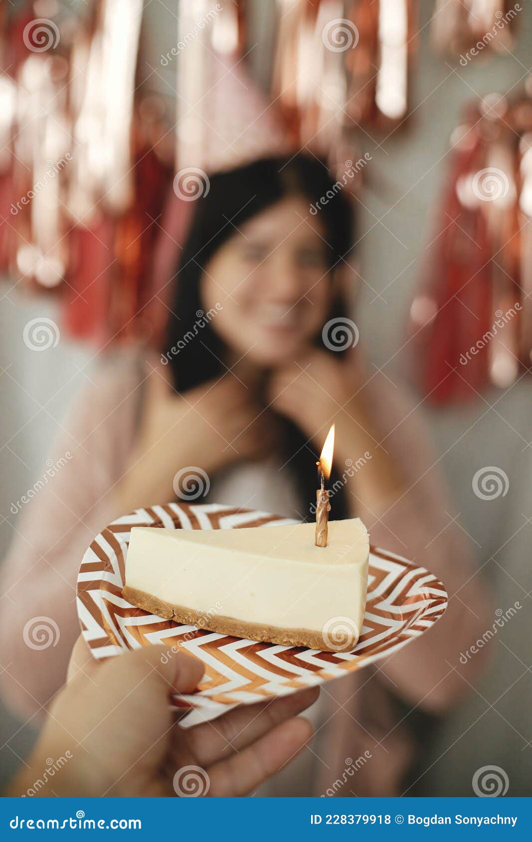 Un Pedazo De Pastel De Cumpleaños Moderno Con Una Vela En Llamas En La Mano  Sobre El Fondo De Una Mujer Feliz Con Sombrero De Fies Foto de archivo -  Imagen de