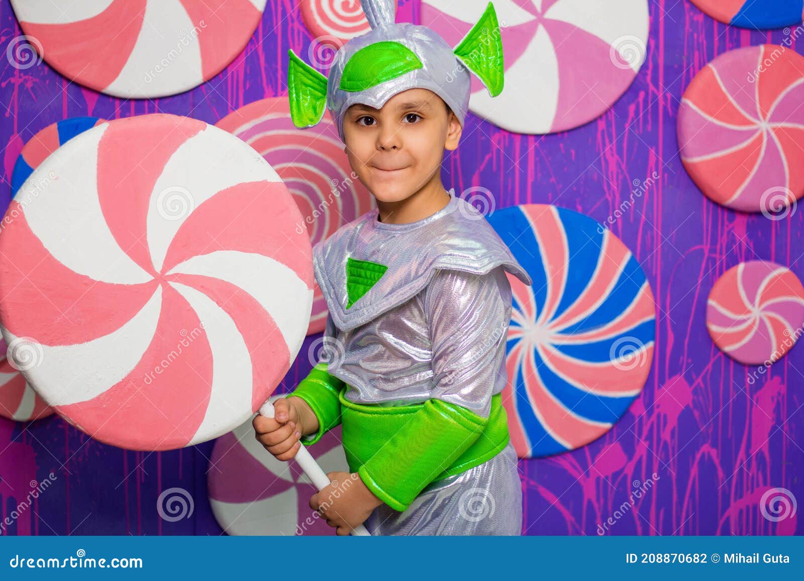 Un Ragazzo in Costume Alieno Tiene in Mano Una Caramella Sullo Sfondo Di Un  Muro Di Dolci Fotografia Stock - Immagine di uomo, bambino: 208870682