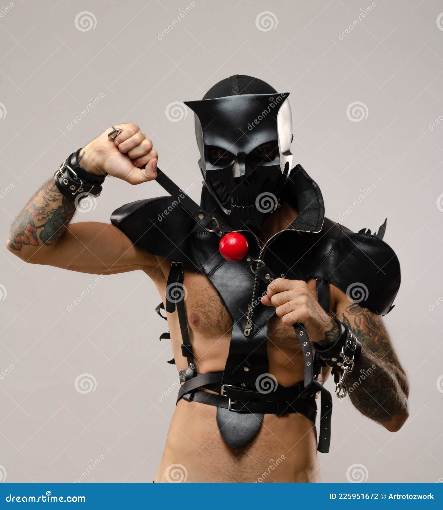 Uomo con una maschera bdsm di un teschio di demone vestito di pelle con  bracciali e cinture in pelle