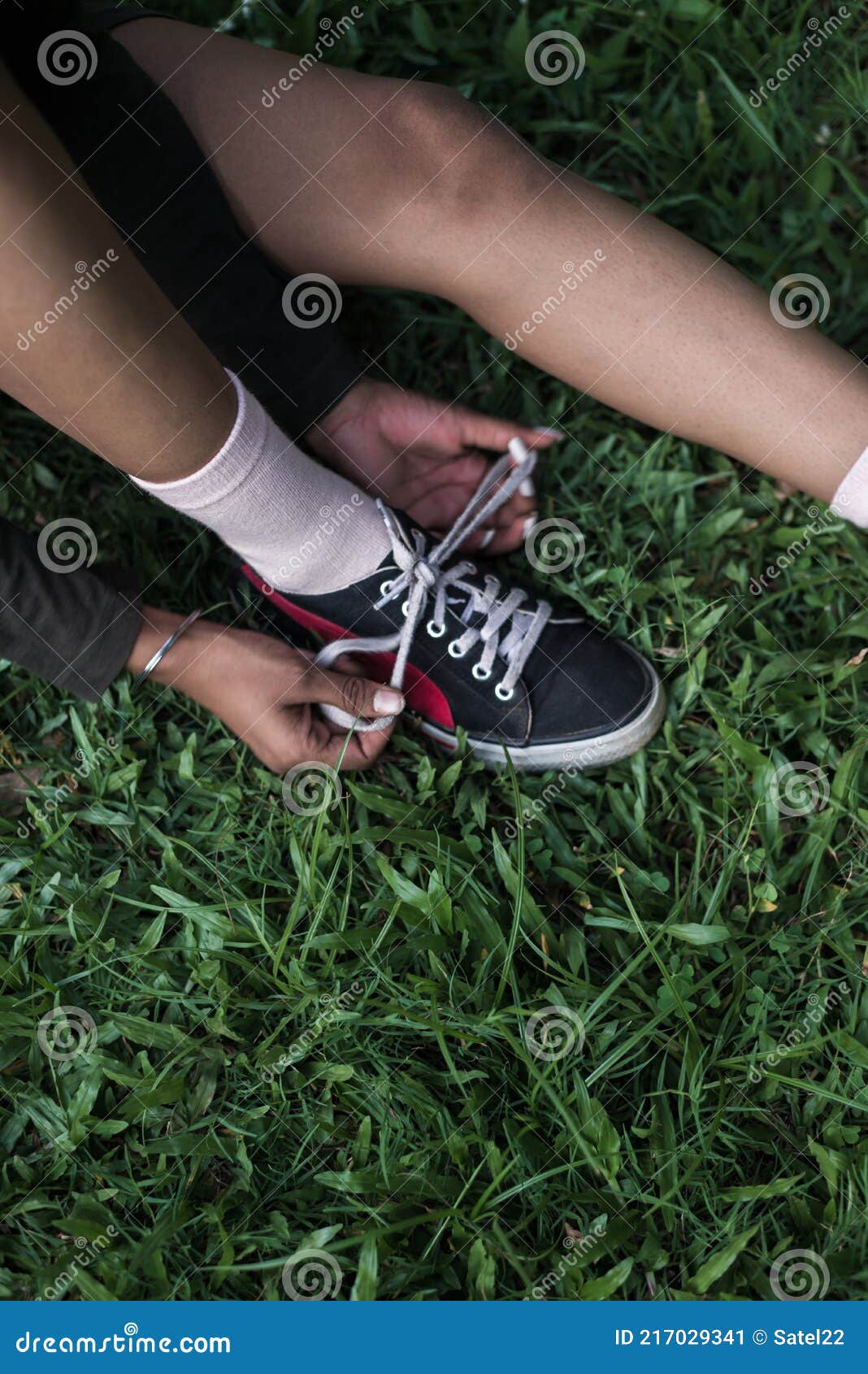 Una Adolescente Atando Un Encaje De Zapato En La Hierba Verde. Imagen de  archivo - Imagen de moderno, tobillo: 217029341