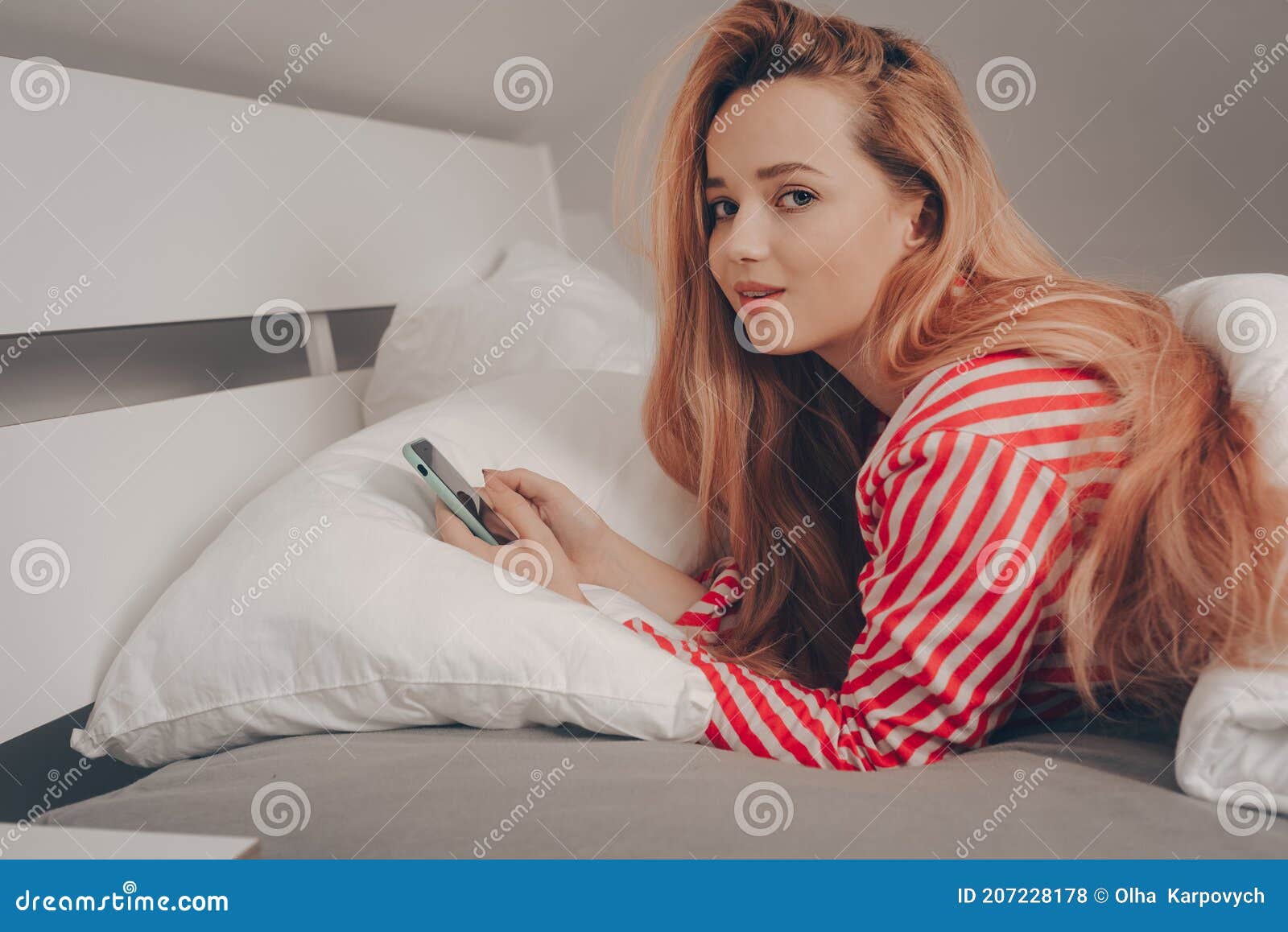 Una Bella Chica Con Cama Blanca Con Pijama Rayada Roja No Puede Dormir Mira Teléfono. Sin Dormir Un Smartphone En Manos Foto de archivo - Imagen de lifestyle, social: