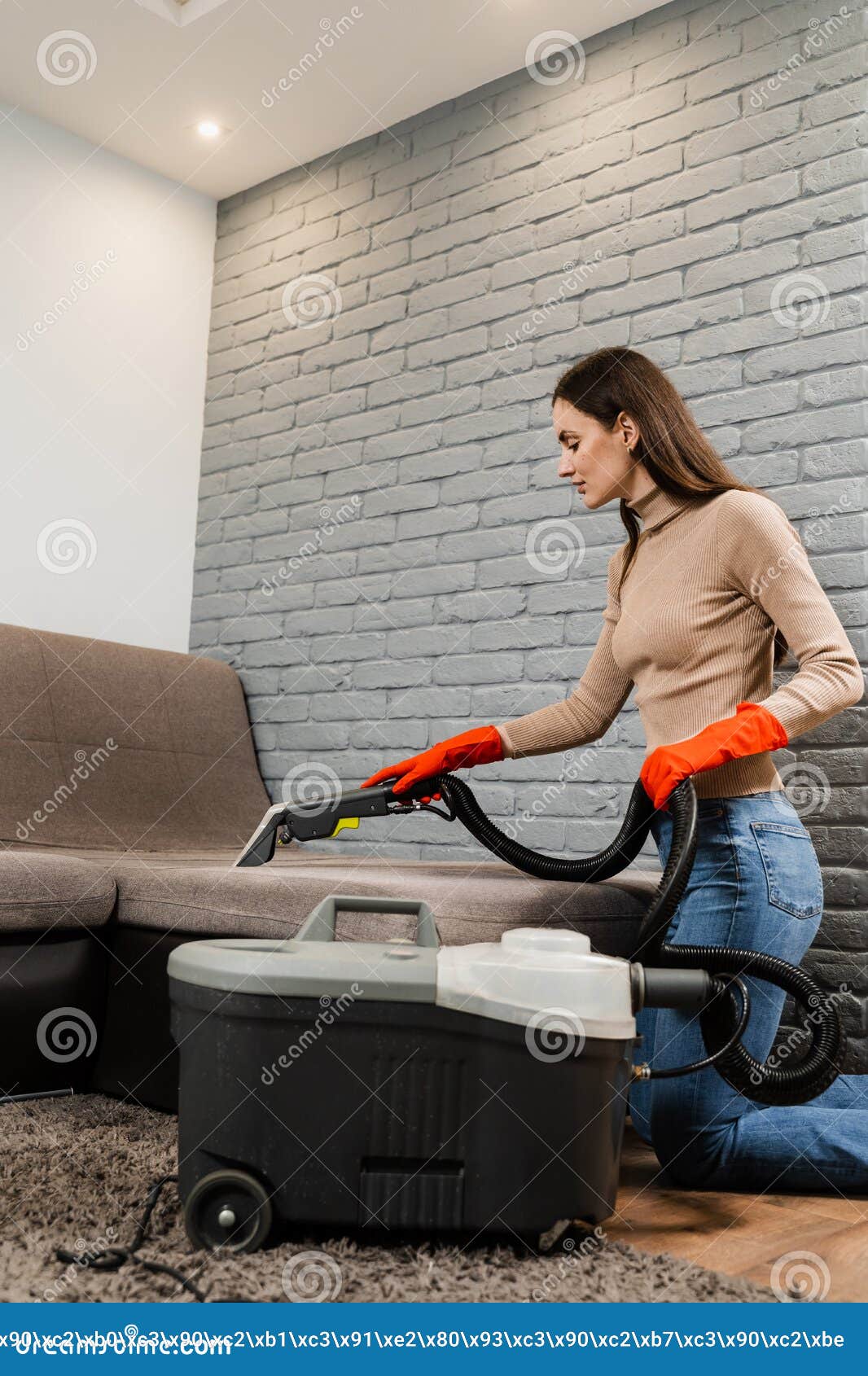 La chica limpiadora está limpiando el sofá con una máquina de extracción  para muebles tapizados de limpieza en seco