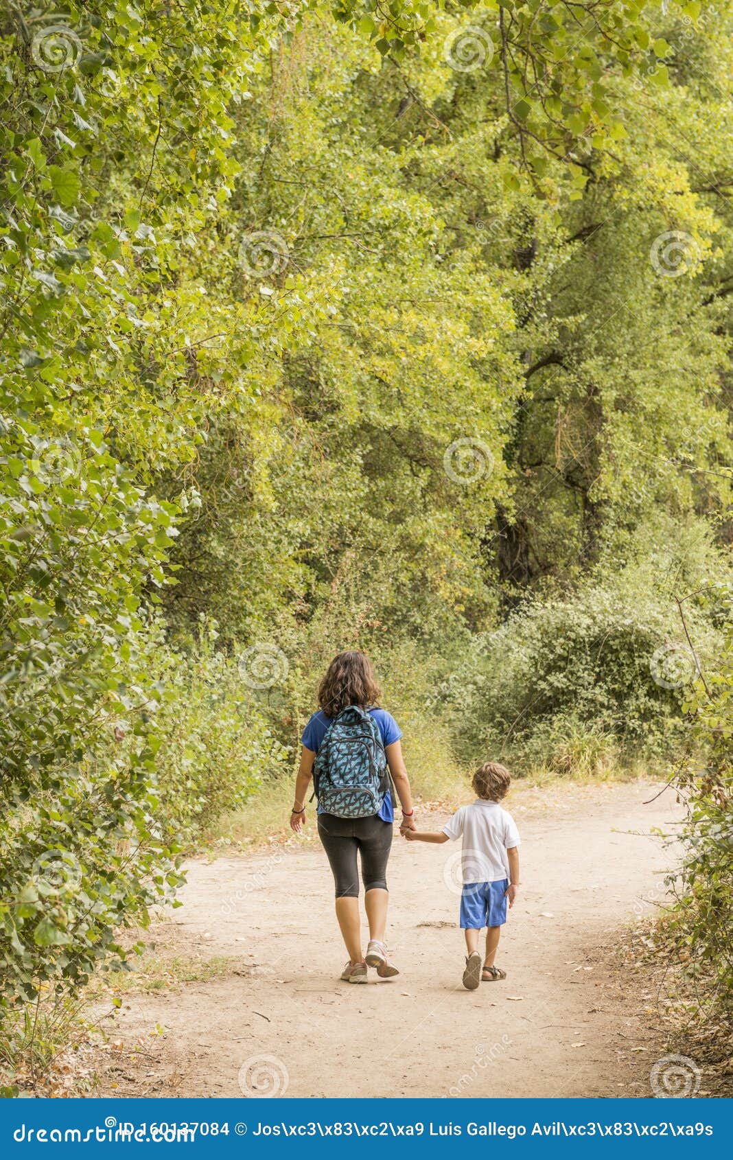 Una donna e un bambino che fanno trekking, camminando lungo una strada sterrata. Una donna e un bambino che camminano su un sentiero sporco attraverso una foresta Concetti di stile di vita familiare e di vita sana