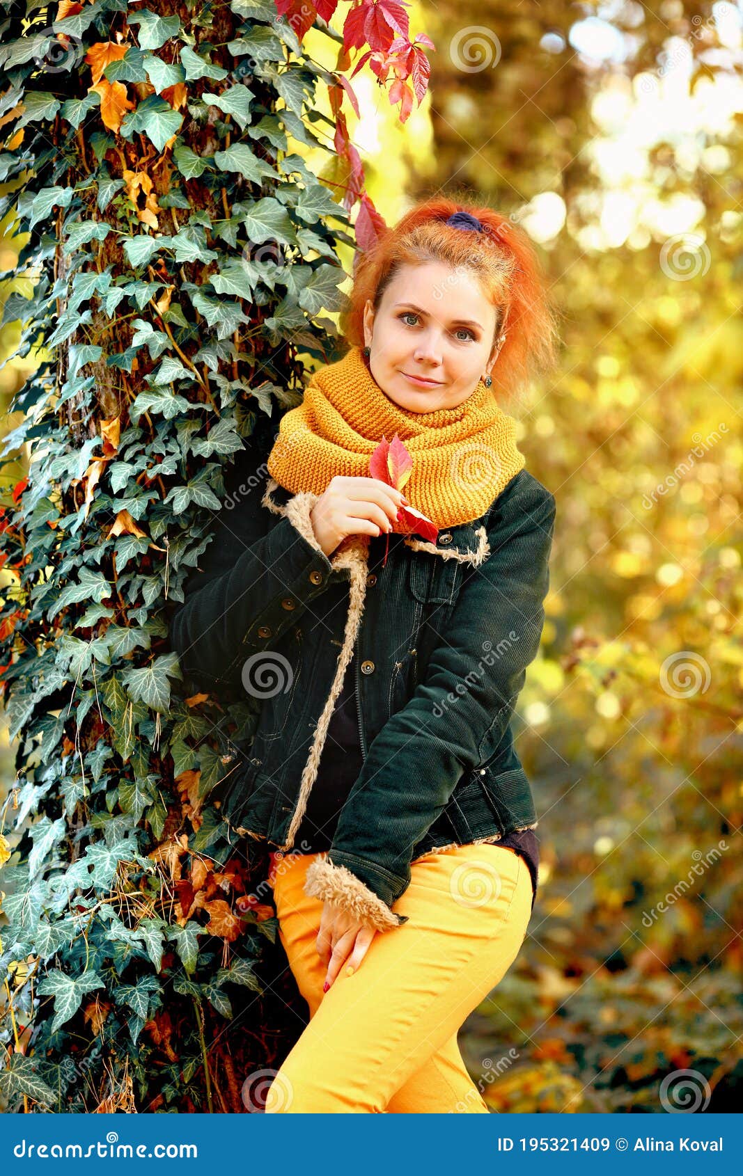 Joven De Cola Roja Camina Por Otoñal. La Chica Está Con Jeans Amarillos Y Una Chaqueta Verde. Mujeres De Oto Imagen de archivo - Imagen de felicidad, exterior: