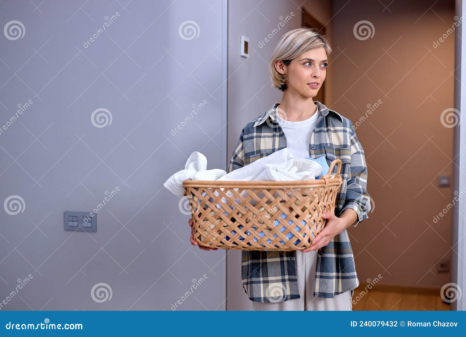 Mujer sosteniendo una cesta de mimbre con ropa limpia