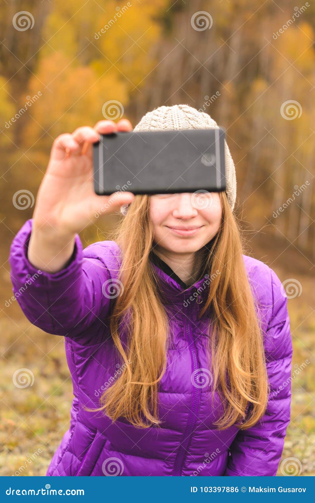 Una muchacha en una chaqueta de la lila hace un salfi en una montaña, una visión de las montañas y un bosque otoñal por un día nublado, espacio libre para el texto