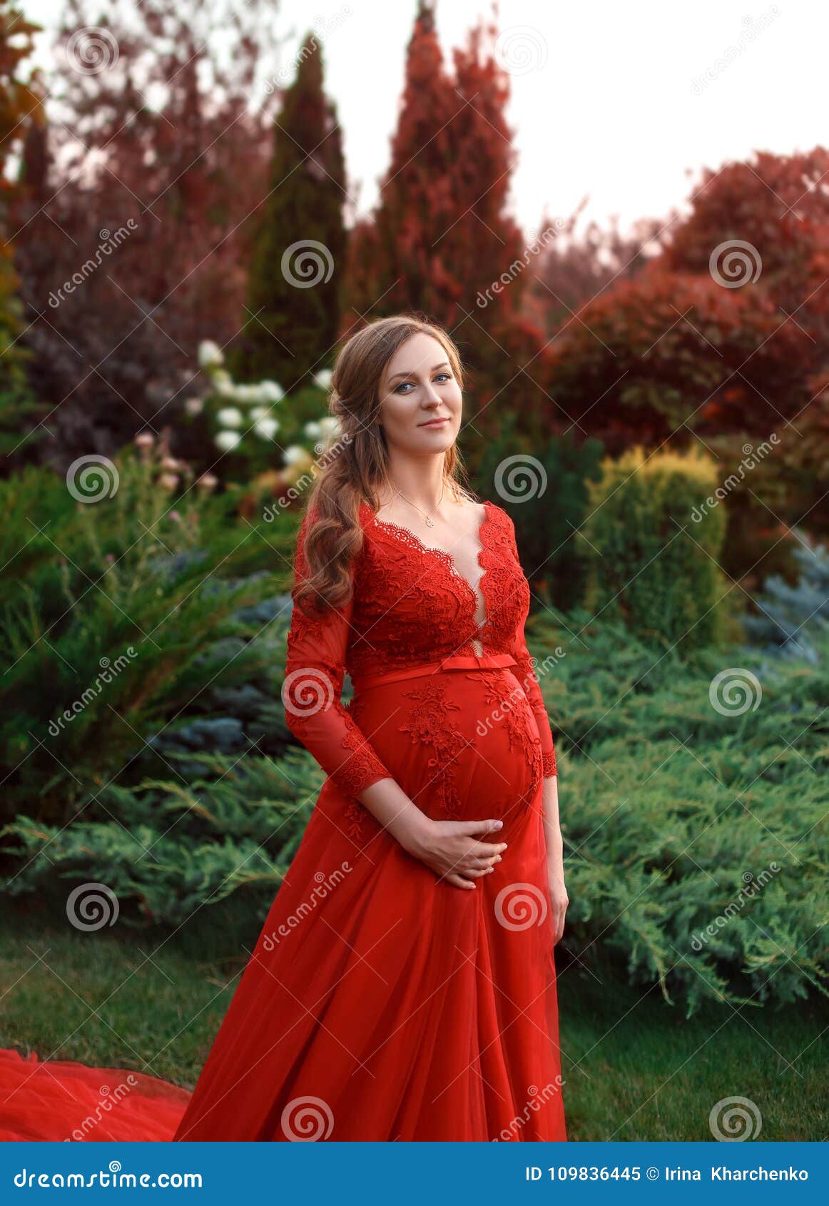 Una Mujer Elegante, Embarazada Camina En Un Jardín En Un Vestido Rojo Costoso Con Un Tren Largo Artístico Imagen de archivo - Imagen de atractivo, mirando: 109836445